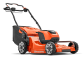 Kosiarka akumulatorowa LC347iVX Husqvarna w kolorze pomarańczowym z czarnymi akcentami. Ujęcie z boku, stojąca, z widoczna przestrzenią na awaryjne wyłączenie. Wyposażona w duże koła z bieżnikiem. Na obudowie widoczne logo Husqvarna.