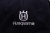 Granatowa czapka z daszkiem Husqvarna z białym haftem logo. Ujęcie zbliżeniowe na tył czapki, ukazujące wyraźne napisy oraz fakturę materiału. Czapka ma charakterystyczny kształt z daszkiem, wykonana z trwałego materiału.