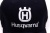 Granatowa czapka z daszkiem Husqvarna, pokazana z bliska, z widocznym białym logo oraz napisem Husqvarna. Czapka ma klasyczny kształt, wykonana z materiału o gładkiej teksturze. Tło białe, co podkreśla detale.