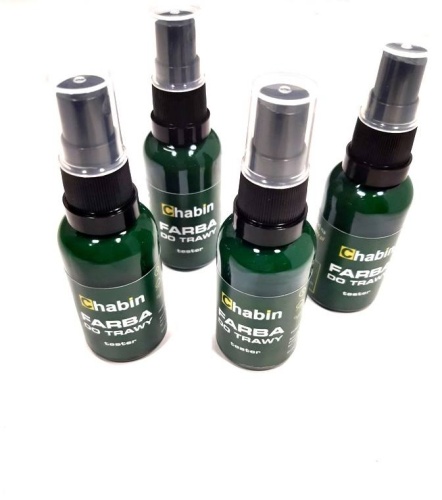Cztery butelki sprayu z farbą do trawy Chabin, ciemnozielone z czarnymi zakrętkami, przezroczystymi nasadkami i etykietą z napisami FARBA DO TRAWY i tester ułożone obok siebie.