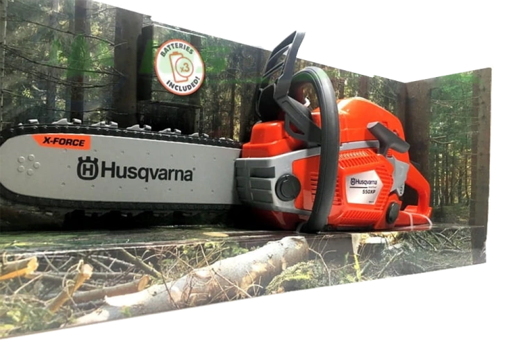 Zabawka dla dzieci pilarka 550XP Husqvarna w kolorze pomarańczowym i szarym. Zademonstrowana w pozycji leżącej, z widocznym logo Husqvarna. Ujęcie z boku, na tle leśnym. Wysoka jakość detali, wyraźne napisy, widoczna piła z elementem X-FORCE.
