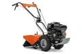 Kultywator TR 348 Husqvarna w pomarańczowym kolorze, widoczny z boku z silnikiem po prawej, dużymi gumowymi kołami i metalowym wirnikiem z przodu. Na uchwycie napis 'Husqvarna', tło czarne.