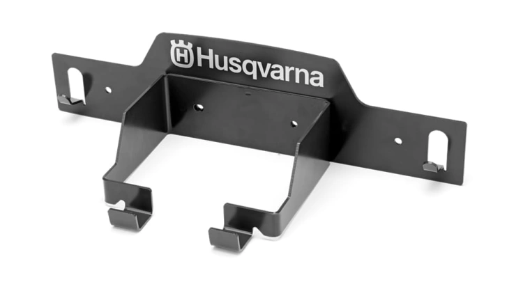 Wieszak na kosiarkę Automower Husqvarna, kolor czarny, metalowy. Ujęcie frontalne, produkt zamontowany, widoczne logo Husqvarna. Elementy mocujące w dolnej części, przeznaczony do przechowywania kosiarki. Proste tło podkreślające formę produktu.