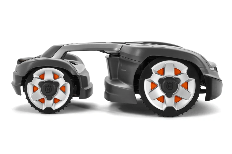 Automower® 435X AWD robot koszący Husqvarna, widok boczny, duże szare koła z metalicznymi obręczami i pomarańczowymi detalami, opływowy kształt, marka widoczna, jednolite tło.