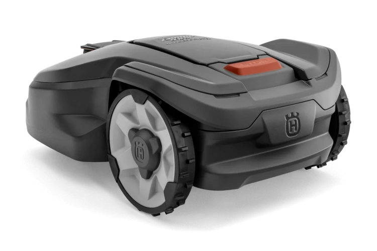 Robot koszący Husqvarna Automower® 310 Mark II w kolorze szarym z białymi detalami. Ujęcie z boku, zbliżenie na detale oraz logo na obudowie. Widoczne gumowe koła i przycisk startowy w kolorze pomarańczowym. Produkt leżący, minimalistyczne tło.