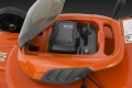 Akumulatorowa kosiarka LC142i Husqvarna z otwartą pokrywą, ukazującą miejsce na akumulator i wbudowane elementy sterujące. Widać logo Husqvarna oraz czytelne wskaźniki na baterię. Produkt w intensywnym pomarańczowym kolorze z czarnymi detalami.