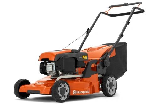 Kosiarka Husqvarna LC 247+ w kolorze pomarańczowym z czarnym koszem na trawę. Widok z boku, produkt leżący na płaskiej powierzchni. Widoczne logo Husqvarna oraz elementy napędu. Stojak do uchwytu w pozycji roboczej.