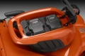Widok z góry na kosiarkę akumulatorową LC347iVX Husqvarna z widocznymi dwoma akumulatorami BL1200. Kosiarka w odcieniach pomarańczowym z czarnymi detalami, elementy mocujące i uchwyty są dobrze widoczne. Tło w jednolitym, ciemnym kolorze.