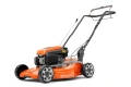 Kosiarka spalinowa LB 256SP Husqvarna w kolorze pomarańczowym z szaro-srebrnymi detalami, ustawiona w pozycji stojącej, z widocznymi dużymi kołami oraz solidną rączką. W tle gładkie, czarne. Zestaw serwisowy GRATIS dołączony do produktu.