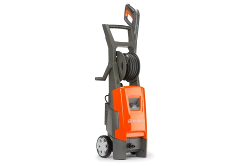 Myjka ciśnieniowa PW 235R Husqvarna w kolorze szaro-pomarańczowym, stojąca. Widok z boku ukazuje wbudowany bęben na wąż oraz logo Husqvarna. Produkt ma klasyczny kształt, z kółkami ułatwiającymi transport. Białe zabezpieczenia na kołach.