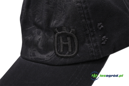 Czarna czapka z daszkiem z haftowanym logo Husqvarna, ujęcie z boku na detal. Materiał teksturowany, z subtelnym wzorem. Widoczne przeszycia i znak firmowy po prawej stronie. Czapka z jonowym daszkiem, idealna do ochrony przed słońcem.