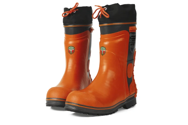 Buty ochronne Husqvarna Functional 24 w kolorze pomarańczowym z czarnym kołnierzem. Wysokie, stojące, z gumowym wykończeniem, mają teksturowaną powierzchnię oraz dwukolorową podeszwę. Widoczne logo na bocznej części oraz wzmocniony czubek.