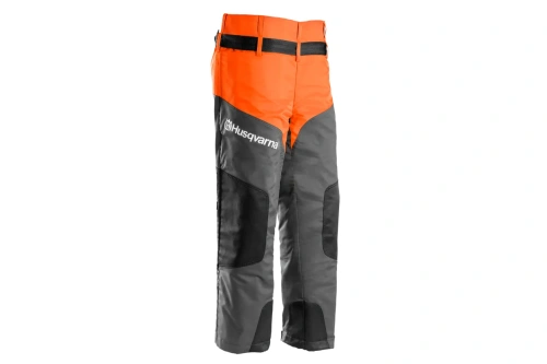 Nogawki ochronne Classic Husqvarna w kolorze pomarańczowym i szarym, z widocznym logo na lewej nogawce. Ujęcie frontalne, produkt stojący. Materiał z widocznymi wzmocnieniami w czarnym kolorze. Regulacja w talii, rozmiar uniwersalny.