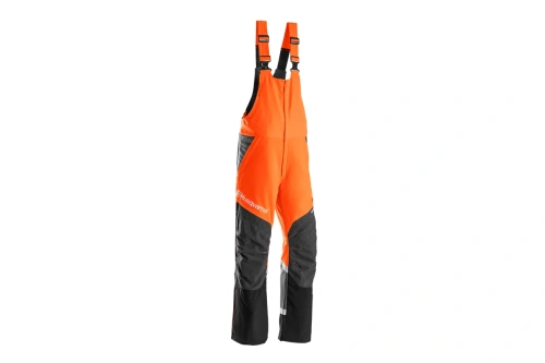 Ochronne spodnie ogrodniczki Husqvarna w kolorze pomarańczowym i czarnym, wykonane z trwałego materiału. Ułożone stojąco, widok frontalny. Widoczne logo Husqvarna oraz dwa pojemne kieszenie. Idealne do pracy w terenie.