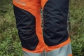 Spodnie ochronne Technical High Viz Husqvarna w kolorze czarno-pomarańczowym z odblaskowymi wstawkami, widoczne panel z logo. Ukazane z zbliżenia na kolana, podkreślają elastyczne wszywki i kontrastowe szwy, idealne do pracy w terenie.