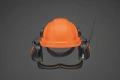 Kask Functional z radiem FM Husqvarna w kolorze jaskrawym pomarańczowym, z zintegrowanymi słuchawkami ochronnymi i siatką na twarz. Produkt widoczny frontalnie, z wyraźnymi detalami regulacji i anteną radio. Tło jednolite, ciemne.