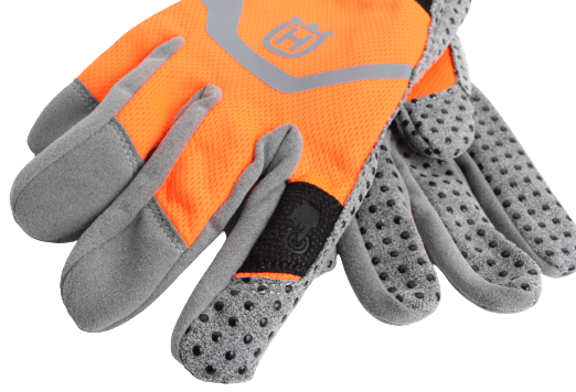Rękawice Functional Light Vet Husqvarna w kolorze pomarańczowym z szarymi akcentami. Spód pokryty materiałem z fakturą o drobnych otworach, logo Husqvarna widoczne na dłoni. Produkt w pozycji leżącej, ukazujący detale wzoru i wykończenia.