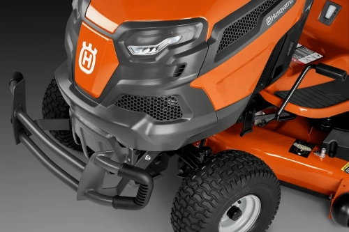 Pomarańczowa osłona maski zderzaka traktora Husqvarna z szarymi detalami, logo i siatką wentylacyjną, na podeście, z nowoczesną fakturą.