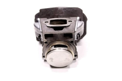 Cylinder kompletny pilarki Husqvarna 560XP/562XP z metalową obudową, widok frontalny. Na zdjęciu widać tłok, komorę ssącą oraz przylgi mocujące. Produkt w nowym stanie, w jasnym otoczeniu. Grafika bez wyraźnych napisów lub logo.