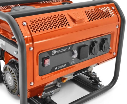 Agregat Husqvarna G3200P, pomarańczowy, metalowa obudowa, panel sterujący z przyciskami i wskaźnikami, stoi na czterech nóżkach, z widocznym logo i elementami montażowymi.