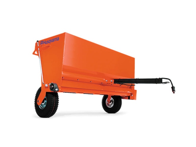 Rozsiewacz Profi Husqvarna, w kolorze pomarańczowym, z tyłu widoczne koła i rurka do podłączenia. Produkt umieszczony w pozycji stojącej, frontalnie ujęty. Na obudowie czytelne logo Husqvarna. Koła z gumowymi bieżnikami.