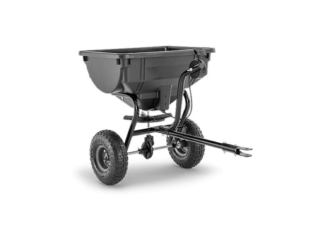 Rozsiewacz Husqvarna 30, czarny, na dwóch dużych kołach. Ujęcie z boku, stojący. Metalowa rama z uchwytem do ciągnięcia. Widoczne mocowanie do traktora. Prosty kształt pojemnika, brak dodatkowych napisów czy zdobień.