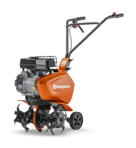Kultywator TF120 Husqvarna w kolorze pomarańczowym z czarnym silnikiem. Ujęcie z boku, stojący. Wyposażony w metalowe ostrza, jednostka z uchwytem i kontrolami na górze. Przeznaczony do pracy w ogrodzie. Tło jednolite.