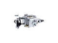 Gaźnik Husqvarna do kosy 545RX, metaliczny, z widocznymi śrubami i elementami mocującymi, ujęcie z boku, na białym tle. Elementy takie jak tłok, zawory i wlot powietrza jasno widoczne, konstrukcja kątowa. Wymiary produktu nieokreślone.