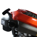 Silnik HS 166A do kosiarki LC253S/LC347V/LC353V Husqvarna w kolorze pomarańczowym z czarnym uchwytem. Widok z boku, pokazujący górną część silnika. Widzoczna siatka wentylacyjna. Przy silniku umieszczony trwały napis instrukcyjny.