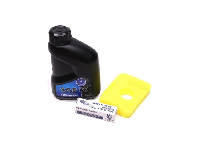 Zestaw serwisowy Husqvarna zawierający czarną butelkę oleju SAE 30, żółty filtr powietrza oraz świecę zapłonową w opakowaniu. Olej oznaczony jest etykietą 4 T oraz logiem Husqvarna, a filtr ma okrągły otwór w centrum.