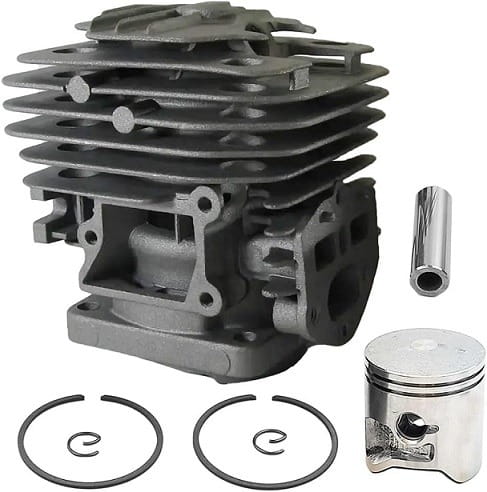 Cylinder pilarki Husqvarna 120, stalowy, szary, z chłodnicą powietrza i zamontowanym tłokiem. W zestawie pierścienie i uszczelnienie. Produkt leży na jednolitym tle, widoczny z boku, ukazujący szczegóły konstrukcji i montażu.