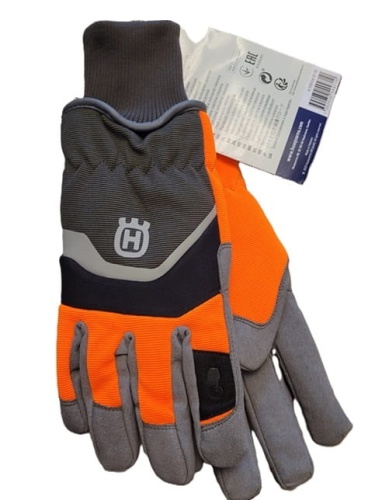 Rękawice ochronne zimowe Husqvarna w kolorze pomarańczowym i szarym, z logo Husqvarna na górze. Produkt z neoprenowym nadgarstkiem i wzmocnionymi palcami. Ułożone w pozycji leżącej, na białym tle. Widoczne etykiety informacyjne w tle.