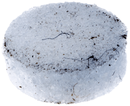 Wkładka odpowietrznika pilarki Husqvarna 335 XPT w kolorze białym, okrągła z delikatną teksturą. Widoczna niejednolitość powierzchni z drobnymi zanieczyszczeniami. Obiekt leży płasko, z góry ukazując kształt i fakturę.