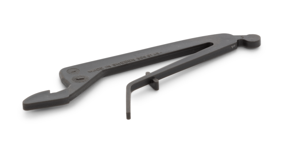 Blokada dźwigni gazu pilarki Husqvarna 40, 45, 49 w kolorze czarnym z matowym wykończeniem. Produkt leży na jasnym tle, widoczny z boku, ukazuje szczegóły konstrukcyjne oraz czytelne oznaczenia MADE IN SWEDEN.