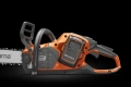 Pilarka akumulatorowa Husqvarna 542i XP, pomarańczowa z szaro-czarnymi elementami, ustawiona pod kątem. Widać uchwyt, panel z kontrolkami i prowadnicę z logo Husqvarna na ciemnym tle.