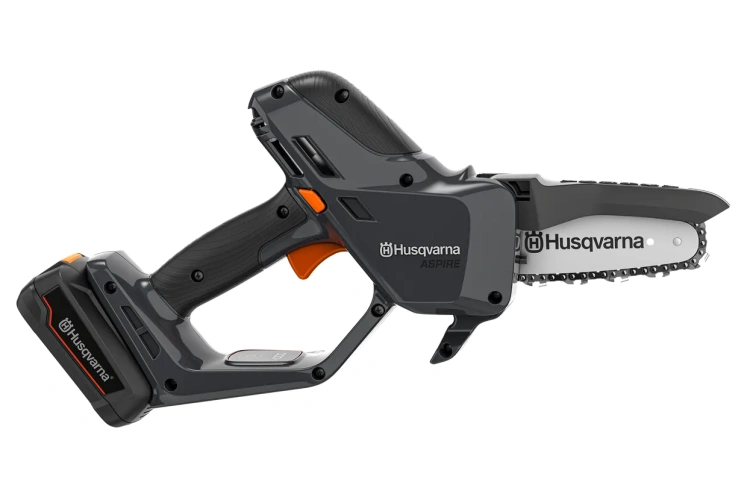 Minipilarka Husqvarna Aspire™ P5-P4A w szarym kolorze z pomarańczowymi akcentami, z akumulatorem i ładowarką. Widoczna prowadnica z trzema zębami łańcucha i ergonomiczna rączka. Akumulator umieszczony u dołu narzędzia.
