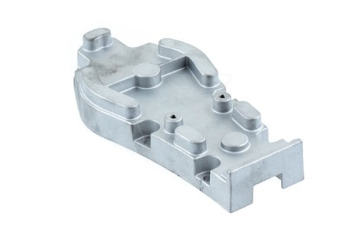 Obudowa przekładni nożyc, wykonana z metalicznego materiału, w kolorze srebrnym. Kształt wyniosły i ergonimiczny, z widocznymi otworami montażowymi oraz wypustkami. Ujęcie z boku, produkt leżący na płaskiej powierzchni.