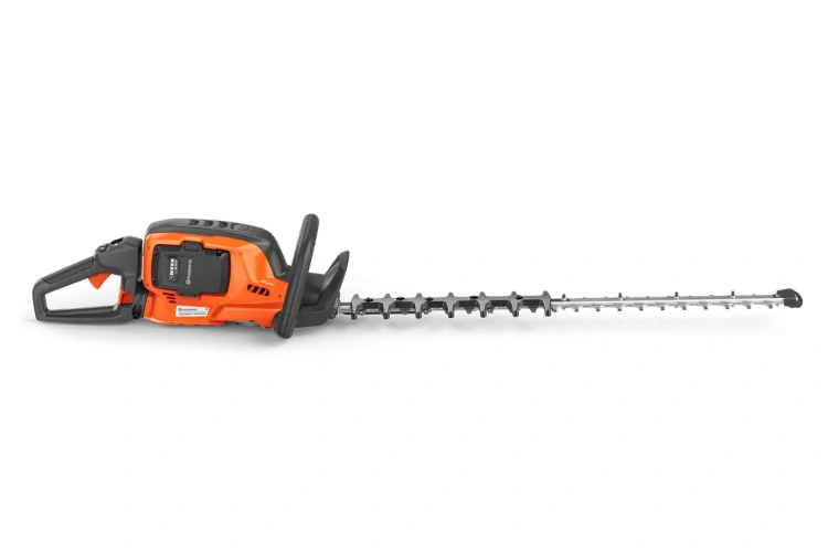Nożyce akumulatorowe Husqvarna 522iHD75 w kolorze pomarańczowym z czarnymi elementami. Produkt leży poziomo, z widoczną ostrą, metalową łopatą tnącą i ergonomicznie ukształtowaną rączką. Ujęcie z boku. Tło czarne.