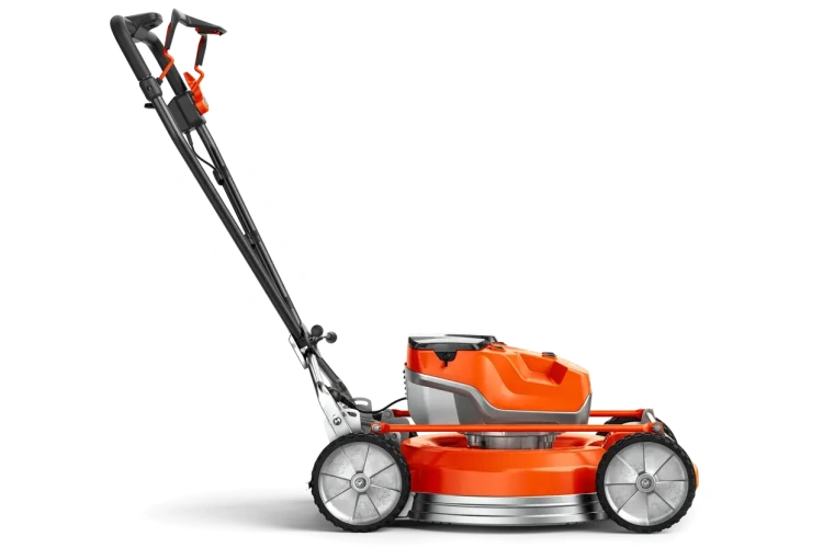 Kosiarka akumulatorowa Husqvarna LB 553iV w kolorze pomarańczowym, z metalową obudową i dużymi, wielołopatkowymi kołami. Ujęcie z boku, produkt w pozycji stojącej, ukazujący uchwyt oraz silnik. Na obudowie widoczna szara dekoracja.