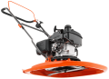 Kosiarka spalinowa Husqvarna GX560 w pozycji stojącej, z boku, na ostrym tle. Posiada metalową, pomarańczową osłonę tnącą oraz wyraźny zbiornik na paliwo. Widoczne elementy silnika i uchwyt ułatwiający obsługę. Kosiarka w stanie nowym.