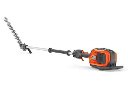 Nożyce do żywopłotu na wysięgniku Husqvarna 525iHE4 w kolorze pomarańczowym z czernią. Produkt w pozycji leżącej, uchwyt z ergonomicznego materiału, długi wysięgnik z metalową końcówką o zębatym kształcie. Tło proste, czarne.