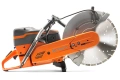 Zagęszczarka Husqvarna LT 6005 w kolorze pomarańczowym z szarymi elementami. Z boku, stojąca pozycja, z wyraźnie widocznym metalowym tarcza tnącą. Logo Husqvarna umieszczone na obudowie. W otoczeniu na jednolitym tle, bez dodatkowych akcesoriów.