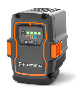Akumulator Husqvarna B140X w kolorze czarnym z pomarańczowymi akcentami, z widocznym wskaźnikiem naładowania i logo. Ujęcie frontalne, produkt stojący na płaskiej powierzchni, z wyraźnymi detalami konstrukcyjnymi.