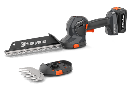 Szare nożyce do krzewów Husqvarna Aspire™ S20-P4A z pomarańczowymi detalami, ostrze 20 cm, akumulator. Leżące, w zestawie małe narzędzie do trawy z zaciskiem, na jasnym, jednolitym tle.