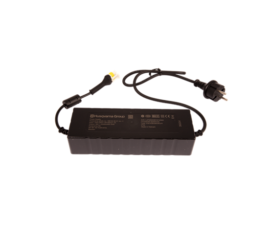 Zasilacz 2.2A w kolorze czarnym z logo Husqvarna na górnej części. Produkt leży płasko, z widocznymi przewodami zakończonymi wtykami. Złącze elektryczne w standardzie krajowym, tekstura obudowy lekko żłobiona dla lepszego chwytu.