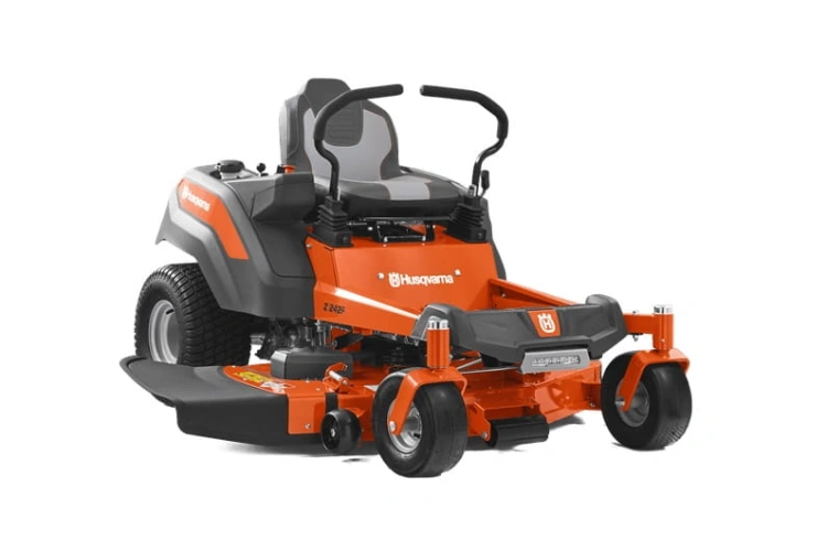 Kosiarka o zerowym promieniu skrętu Z242F Husqvarna w kolorze pomarańczowym z szarym siedziskiem. Ujęcie z boku, produkt ustawiony na ziemi. Widoczne koła, podstawa tnąca oraz uchwyty sterujące. Logo Husqvarna na obudowie.