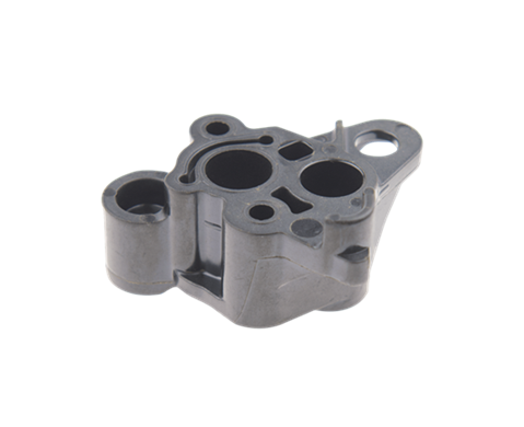 Adapter gaźnika wykaszarki Husqvarna 125R/128R/124L, w kolorze ciemnoszarym, wykonany z tworzywa sztucznego. Widoczne dwa otwory oraz jeden mniejszy, lekko zaokrąglony kształt. Produkt leży na jasnym tle, co podkreśla jego formę i detale.