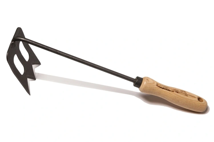 Motyczka SPORK Krumpholz z wygiętym, metalowym ostrzem w kolorze czarnym oraz drewnianą rączką, leżąca na jasnym tle. Ostrze ma specjalne żłobienia, co zwiększa funkcjonalność narzędzia do pielęgnacji roślin.