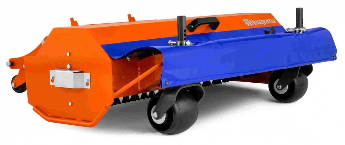 Kosiarka bijakowa do ridera P 524X Husqvarna w kolorze pomarańczowym i niebieskim, z widocznymi uchwytami. Ujęcie boczne, produkt stoi na dużych kółkach, ukazuje detale mocowania i fakturę materiału. Tło jednolite, białe.