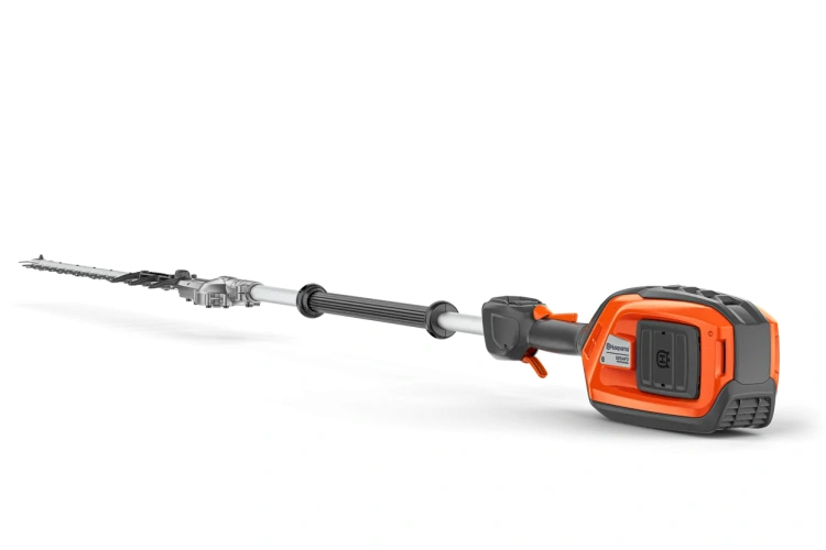 Nożyce do żywopłotu Husqvarna 525iHF3 na wysięgniku, pomarańczowo-szare, z długim zaokrąglonym ostrzem i ergonomiczną rączką, widok z boku, złożone w prawo, z przyciskiem uruchamiającym.